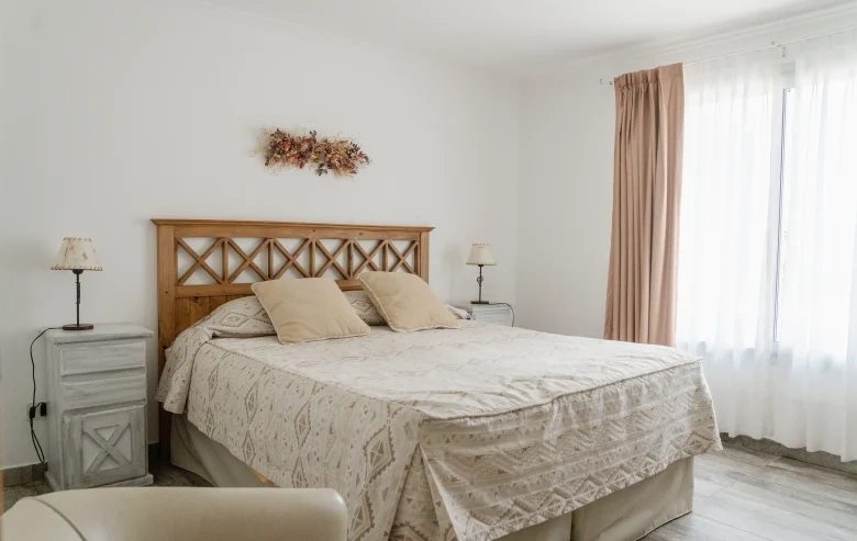 Dormitorio con mesitas de luz, veladores y una ventana con cortinas, correspondiente a la Casa 1