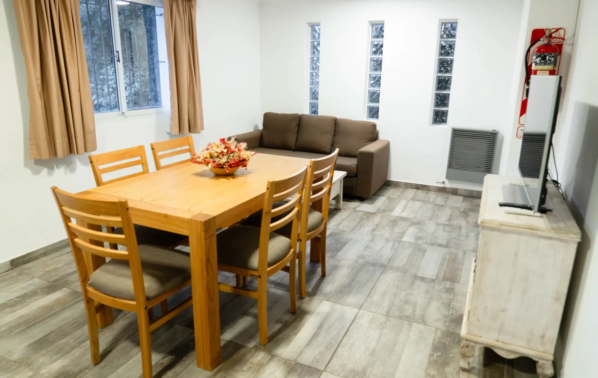Living comedor con mesa y 5 sillas, mesada con televisor y sillón con mesa ratona, correspondiente a la Casa 1