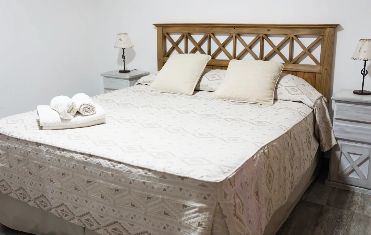 Dormitorio con mesitas de luz, veladores y una ventana con cortinas, correspondiente a la Casa 1