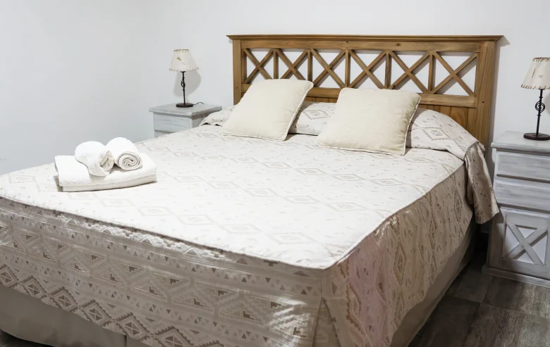 Dormitorio con mesitas de luz, veladores y una ventana con cortinas, correspondiente a la Casa 1