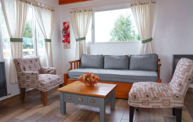Living con sillón de 3 cuerpos y dos sillones simples a los costados, con mesa ratona, 2 calefactores de tiro balanceado y ventanas, correspondientes a la Casa 2