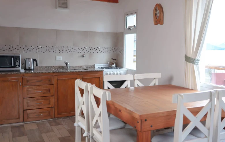 Cocina comedor completa con microondas, pava eléctrica, mesa y 6 sillas, con ventana y vista al lago, correspondientes a la Casa 2