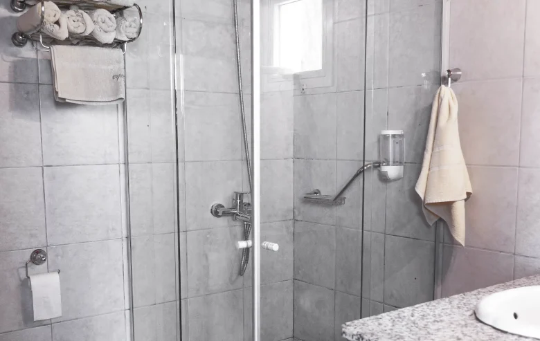 Ducha con mampara de vidrio y toallas a su costado, correspondiente a la Casa 3