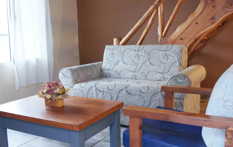 Living con sillón de 2 cuerpos, sillón individual, mesa ratona y escalera de madera, correspondiente a la Casa 4