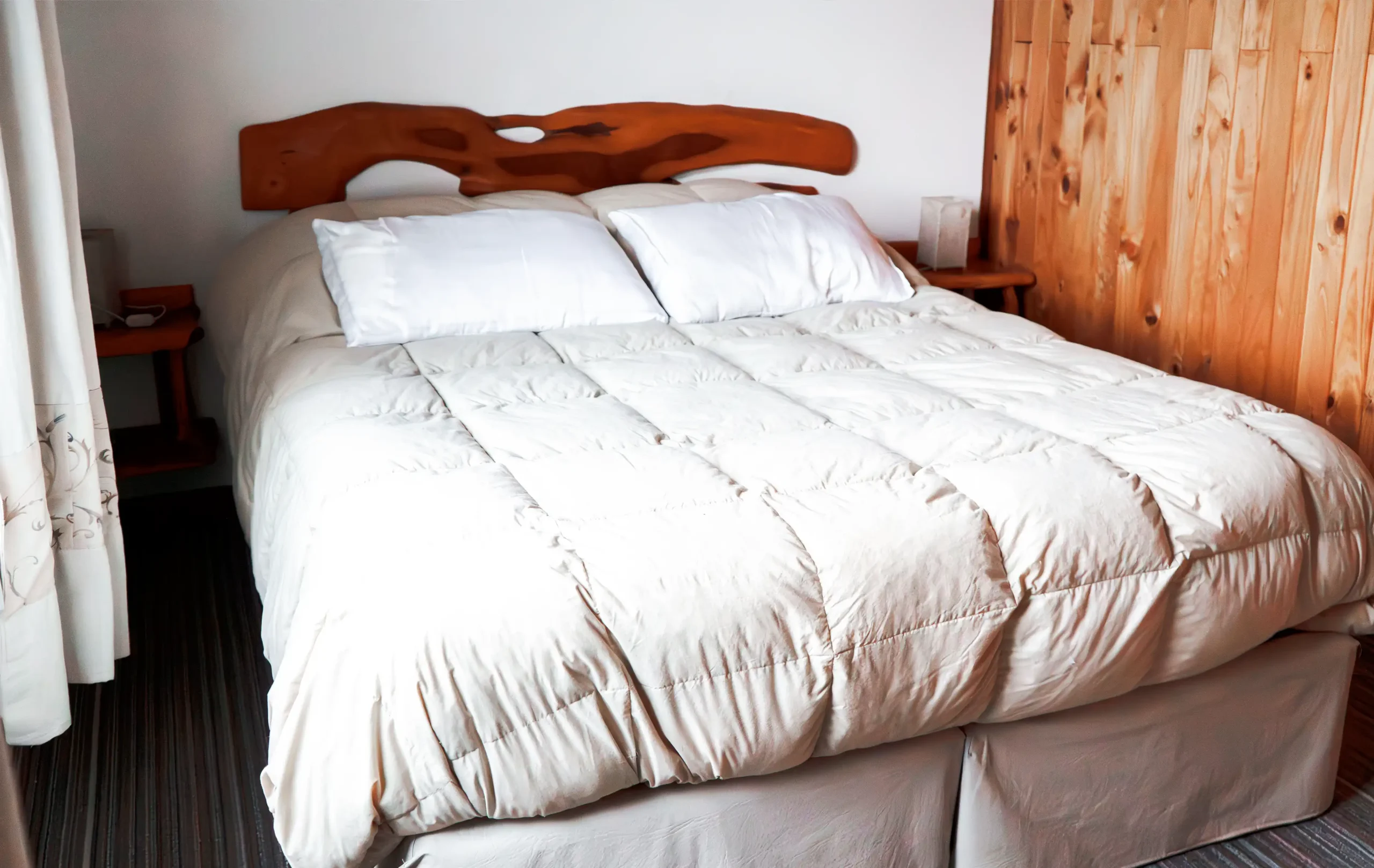 Dormitorio principal con cama matrimonial, acolchado de pluma, mesitas de luz con veladores y ventana con cortinas, correspondiente a la Casa 5