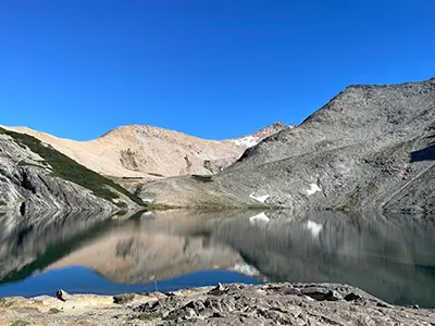 Vista de montañas y lago espejado en día soleado refugio Laguna Negra